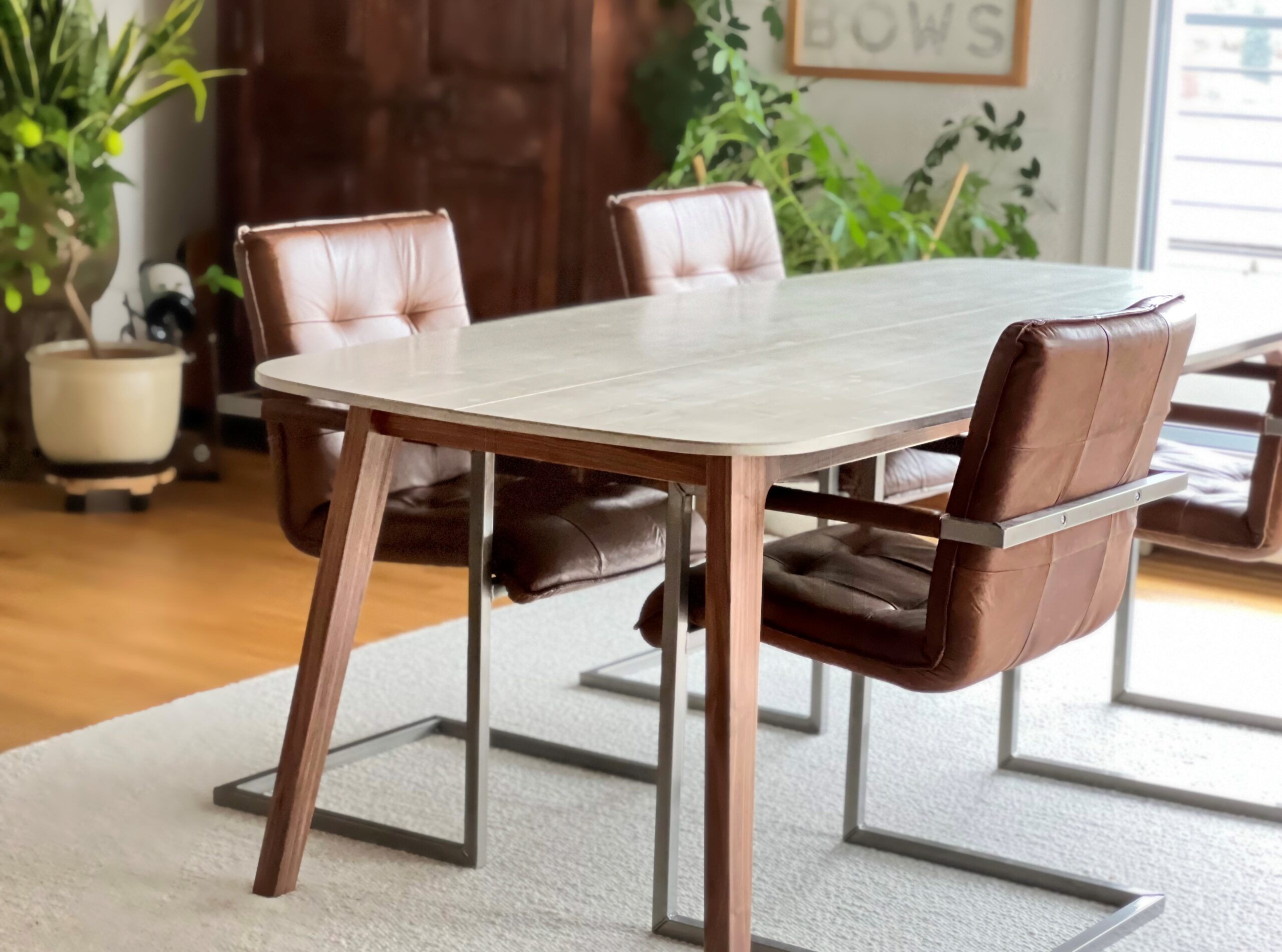 Tisch mit Betontischplatte und Holzbeinen. Dazu Lederstühle